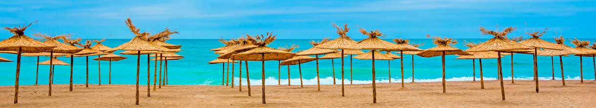 Strohgedeckte Sonnenschirme am Sandstrand
