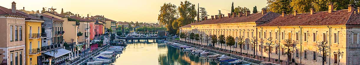 Ein Hafen gesäumt von italienischen Häusern leuchtet im Sonnenuntergang