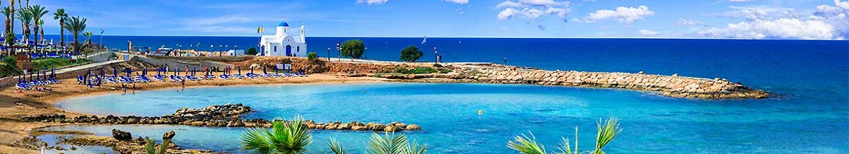 Eine weiße Kirche mit blauem Dach am Strand. 